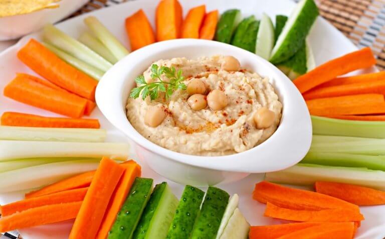 Hummus otoczony słupkami marchwi i ogórka