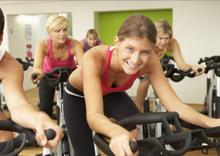 Uśmiechnięte kobiety uprawiające intensywny spinning na sali