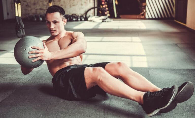 Mężczyzna robiący ćwiczenia mięśni brzucha z piłką lekarską