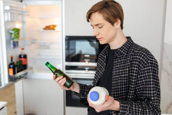 Mężczyzna trzymający w jednej ręce piwo a w drugiej mleko - czy piwo nawadnia?