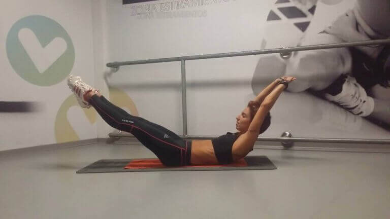 Kobieta unosząca nogi i ręce - ćwiczenia na kształtny brzuch