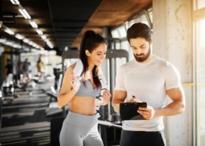 Kobieta z trenerem w siłowni planuje trening aby zapobieganie kontuzjom